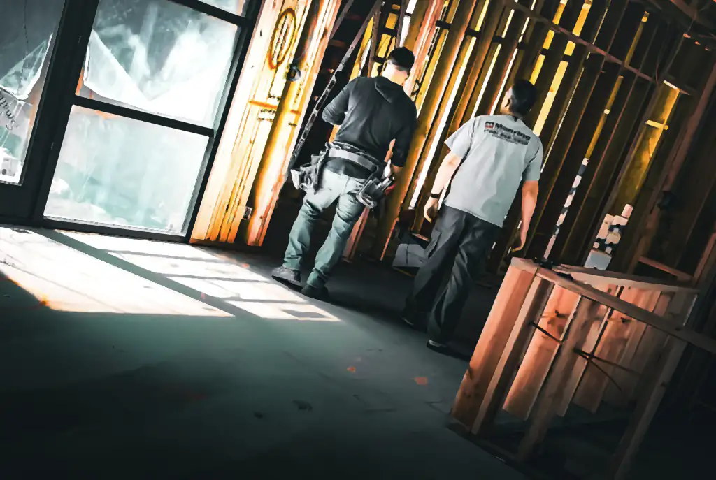 Two men, one in a Manring Heating & Air shirt, walking through a construction site in natural light