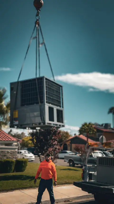 A crane lifts a new rooftop air conditioning unit over a Las Vegas neighborhood