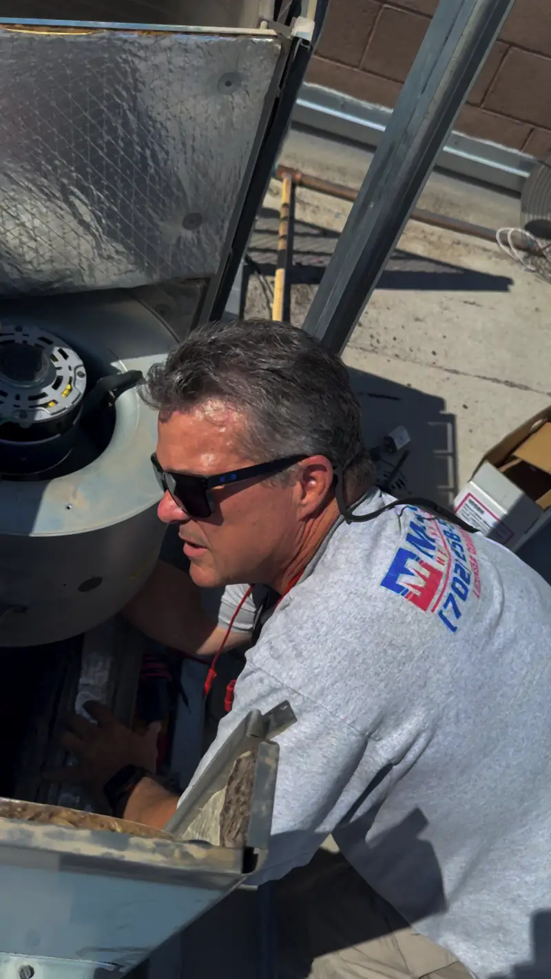 Manring technician in sunglasses diagnosing a rooftop air conditioning unit
