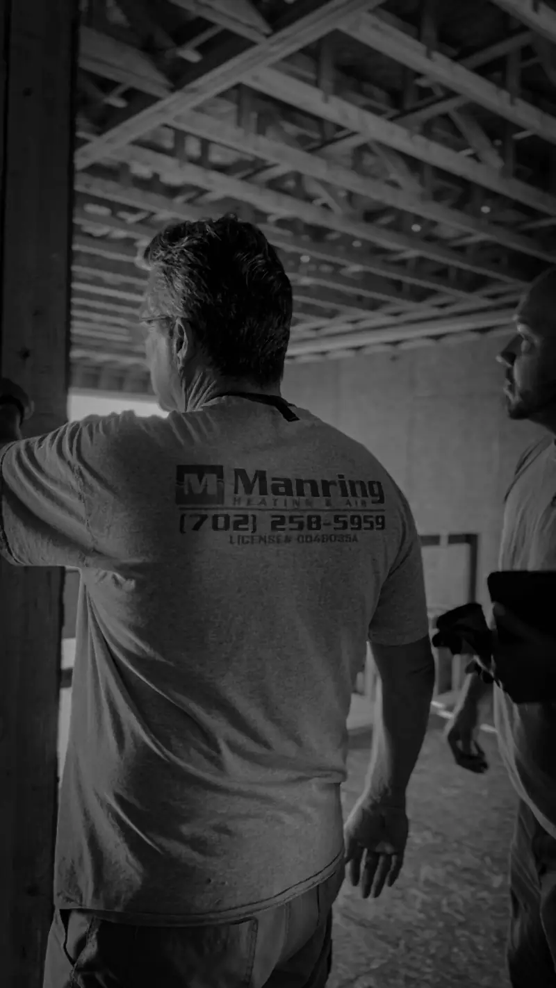 Black-and-white photo of a Manring technician walking through a commercial job site